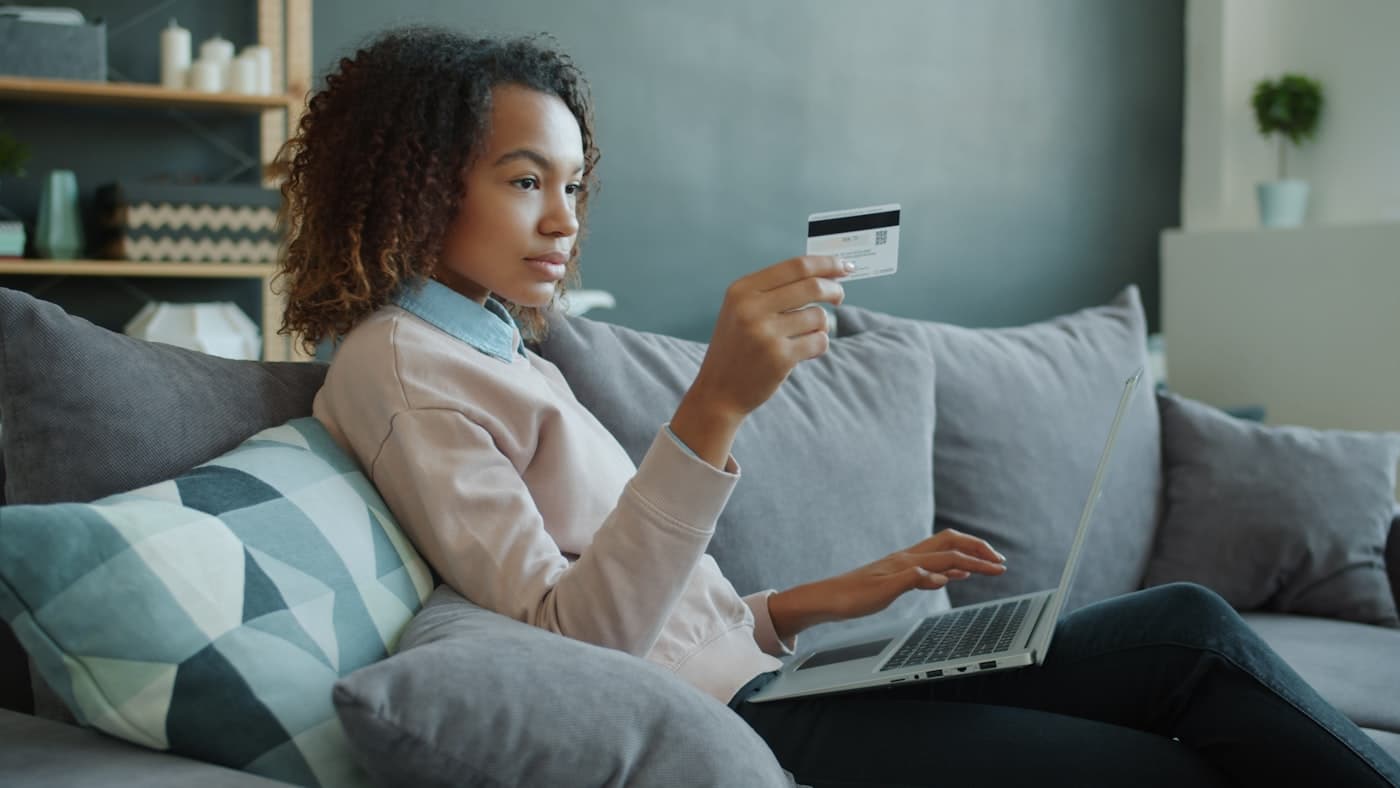 Dizüstü bilgisayar ve kredi kartıyla online ödeme yapan kişi