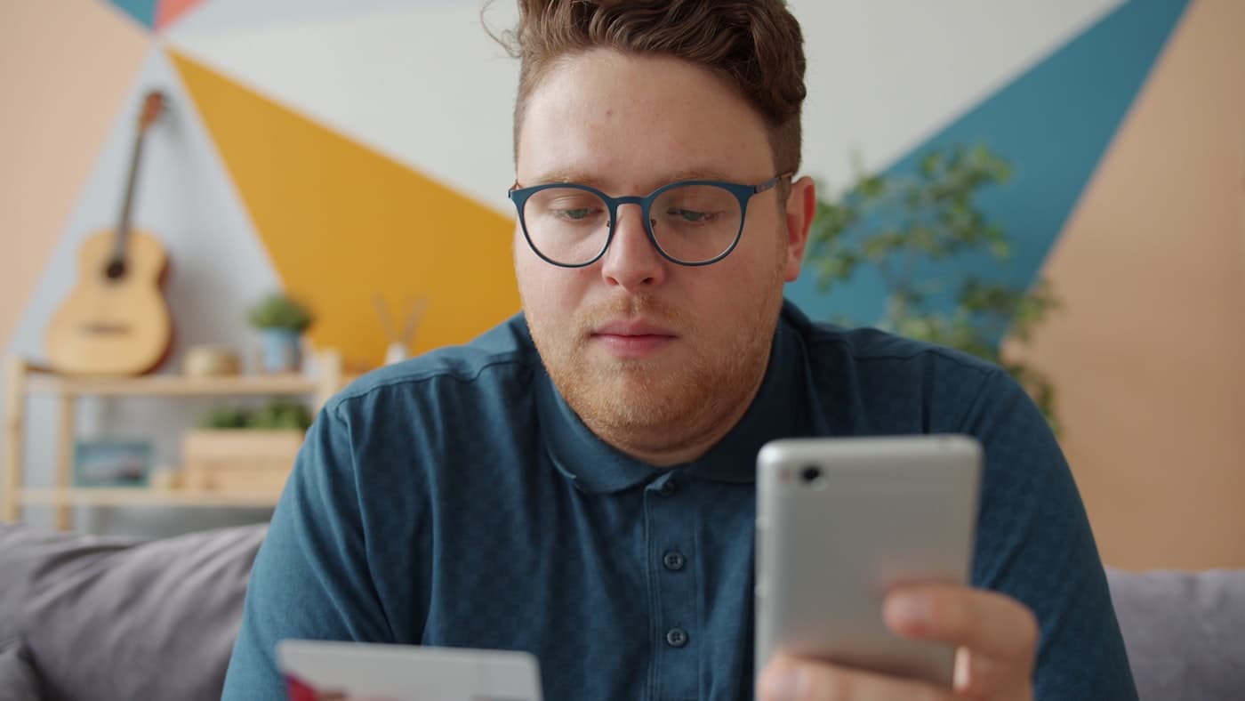 Kredi kartı ve akıllı telefonla online alışveriş yapan kişi